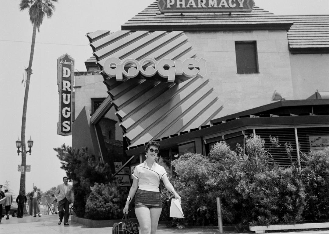 A woman walks outside Googies Coffee Shop and Schwab's Pharmacy in Los Angeles.