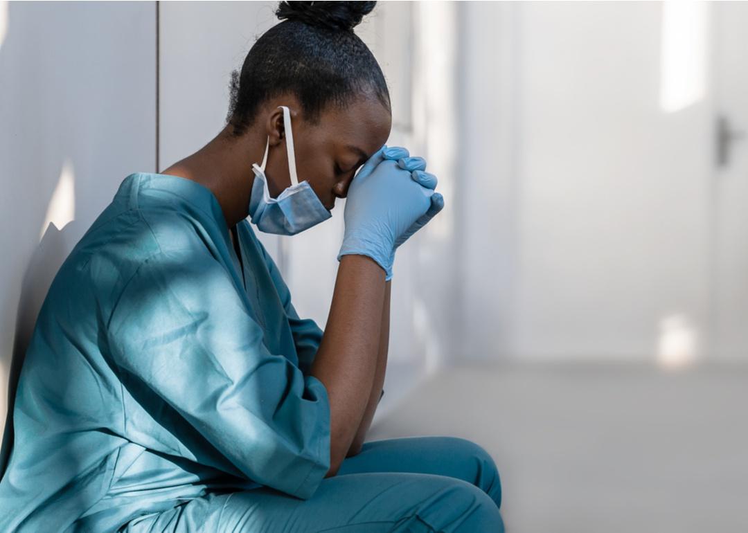 Female health care worker crouched on the floor with head in hands