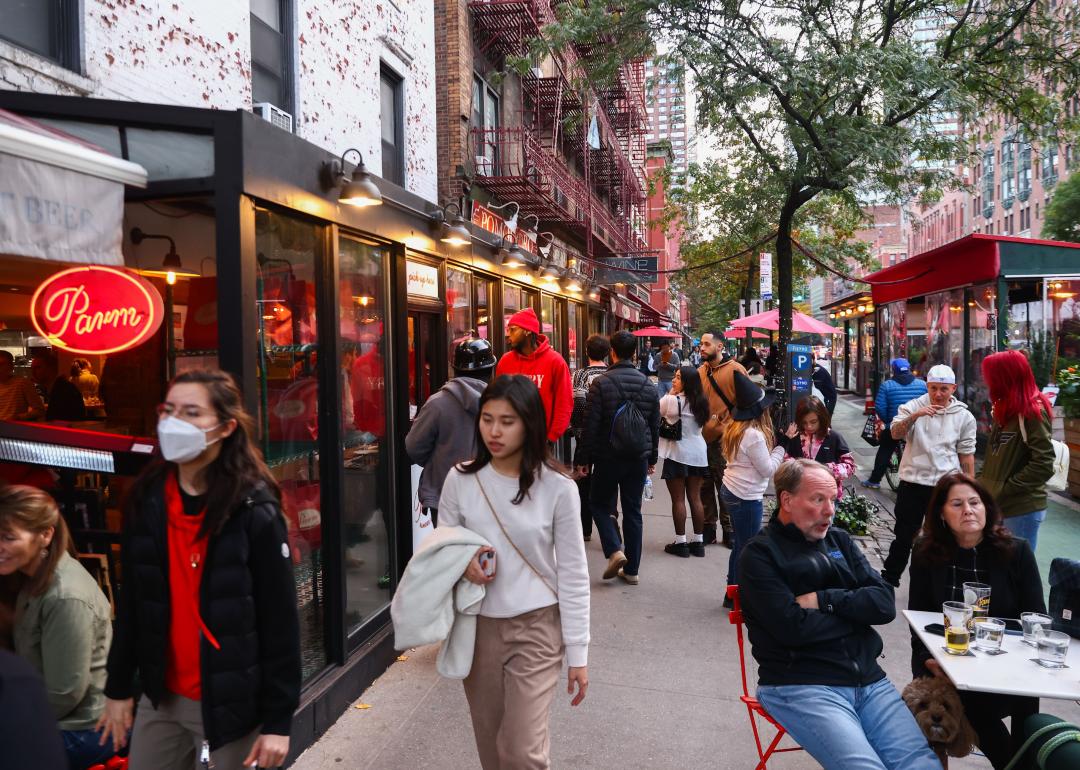 A busy New York sidewalk of people at restaurants.