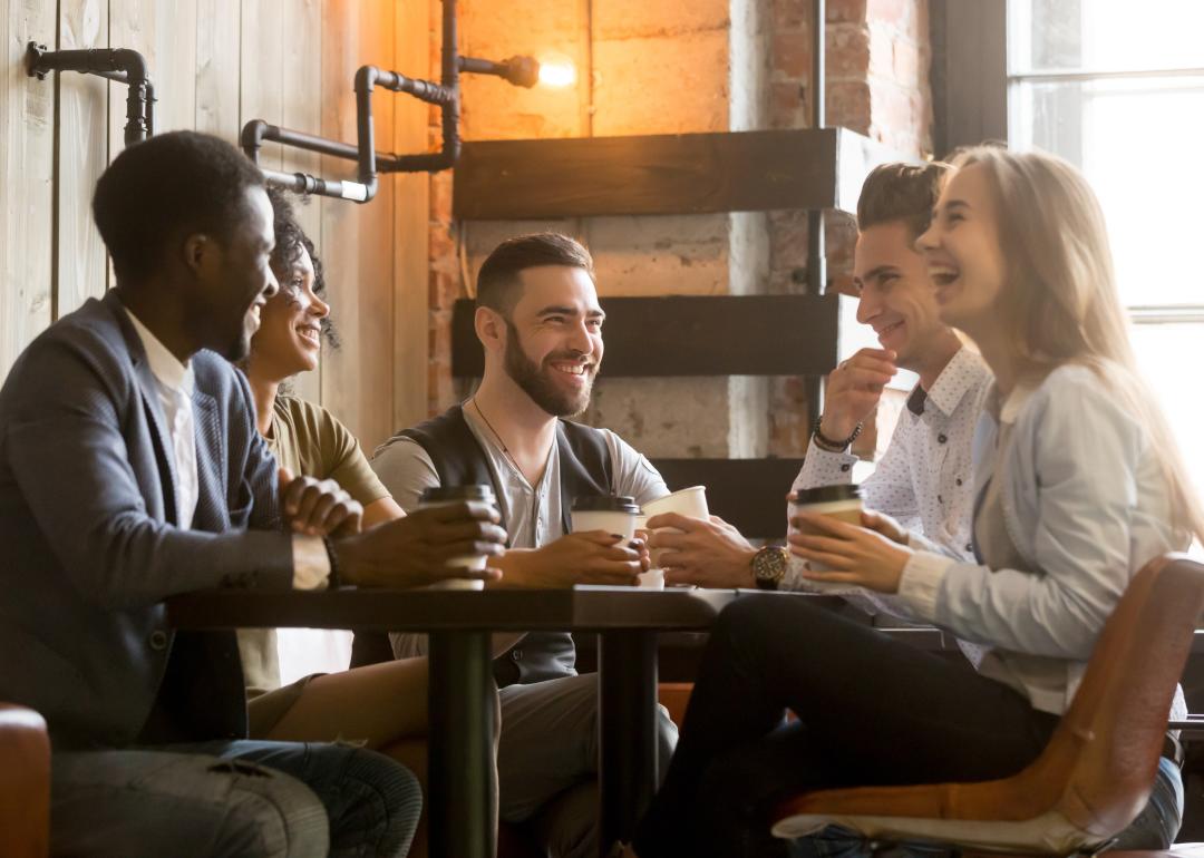Group of friends having fun and laughing drinking coffee in coffeehouse.