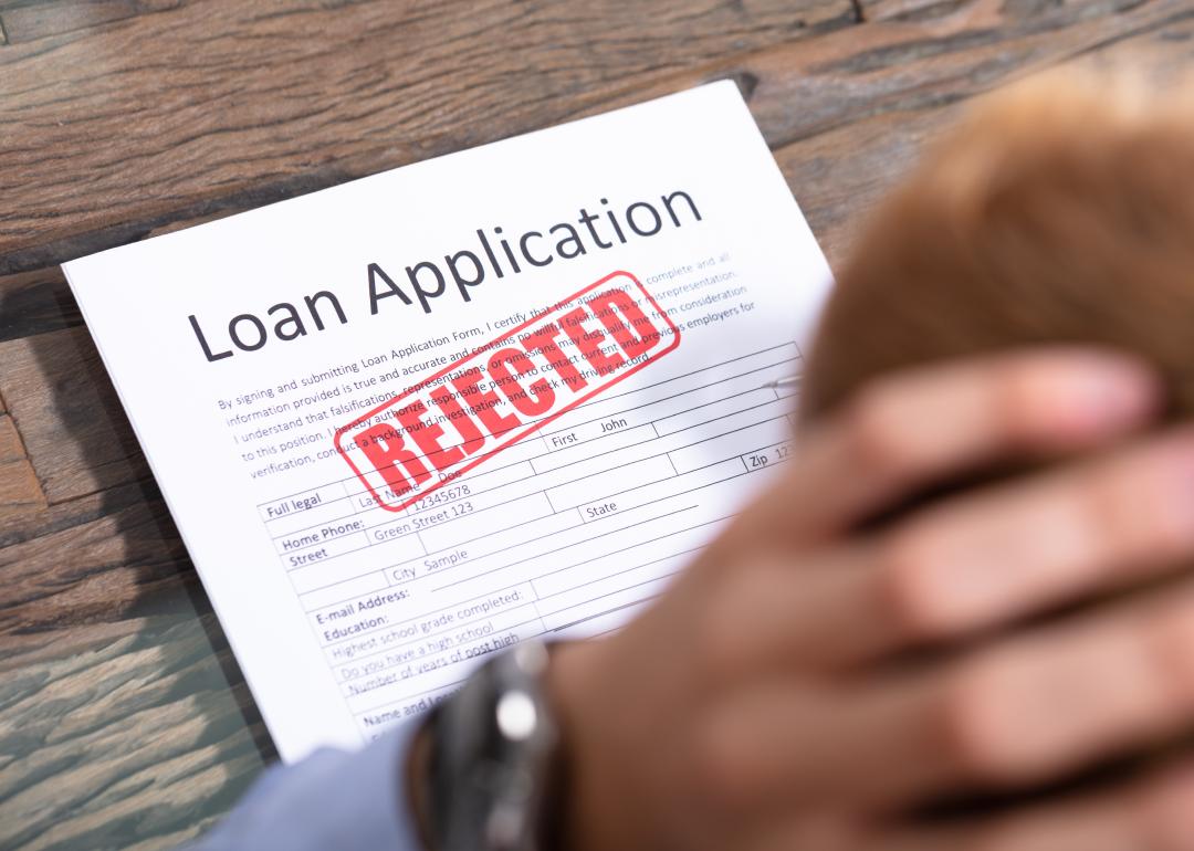 Stressed person looking at a rejected loan application.
