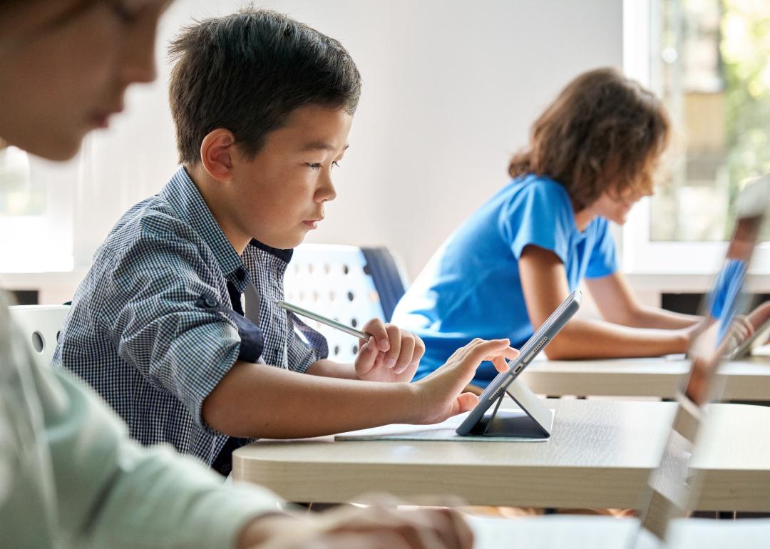 Elementary-aged students using digital tablets in classroom.