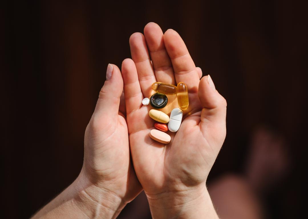 Hands hold supplements on blurred background.