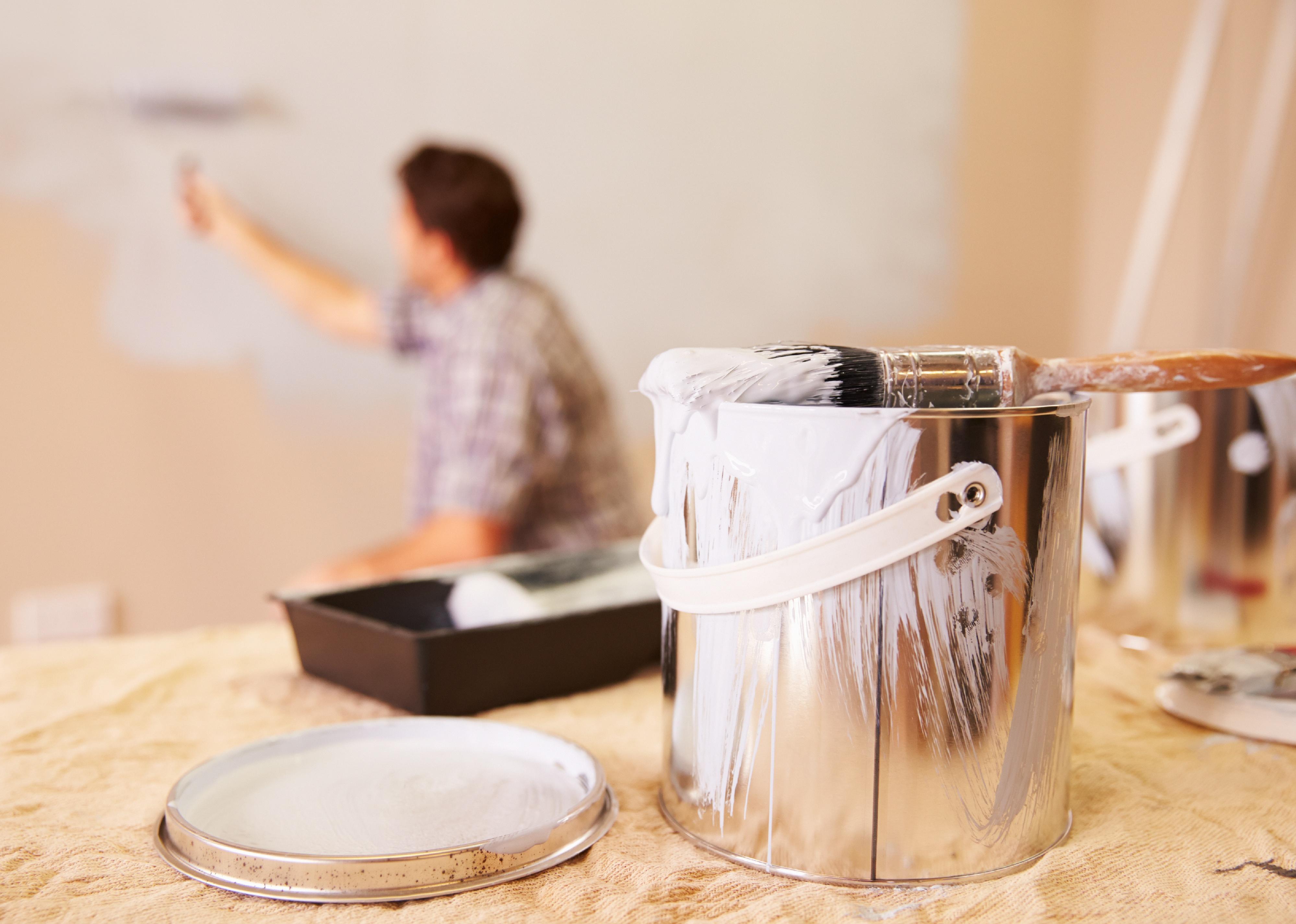 Man decorating room using paint roller on wall.