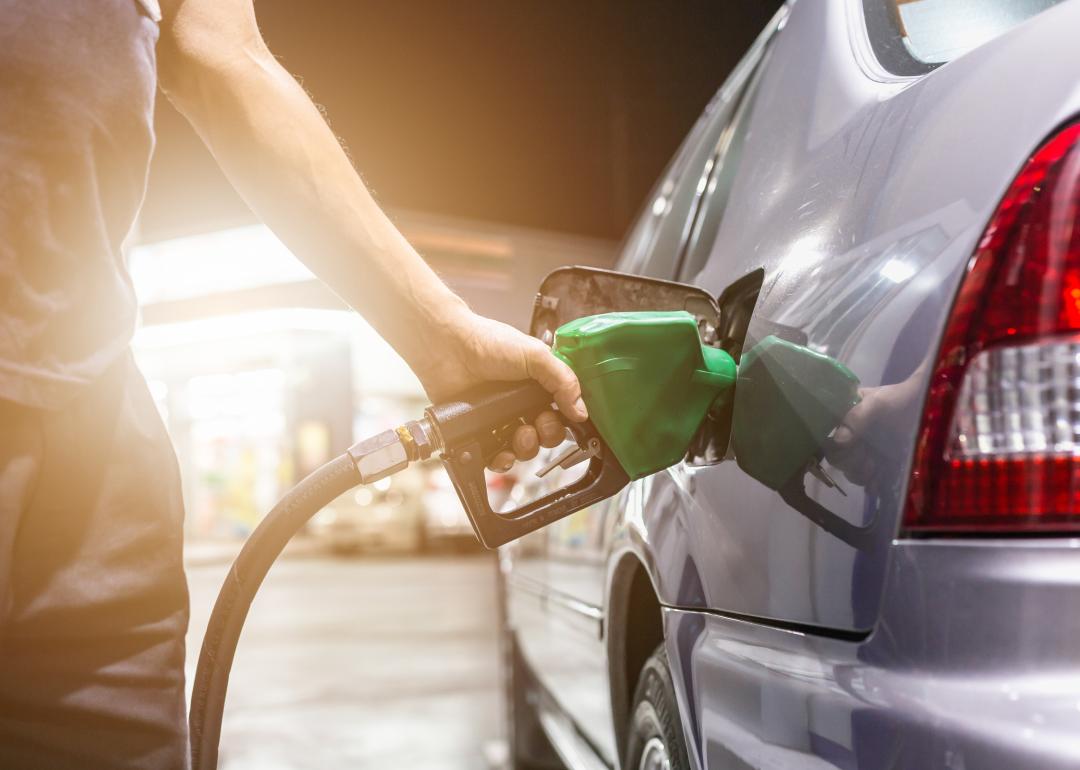 Gray car at gas station being filled.