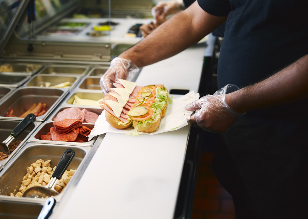 A fast food worker assembling a sandwich