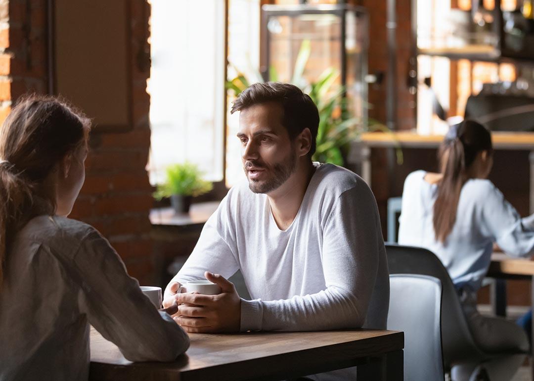 Millenial couple sitting at a cafe table engaged in discussion.