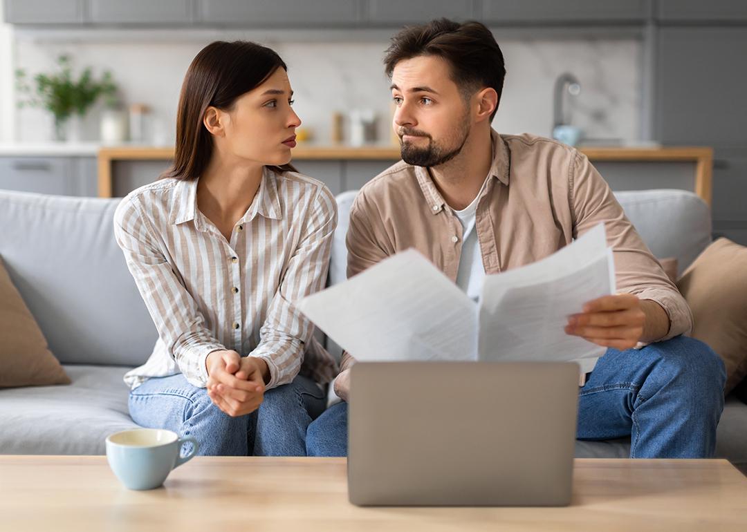 Young couple looking at each other with a serious expression while going through financial documents.