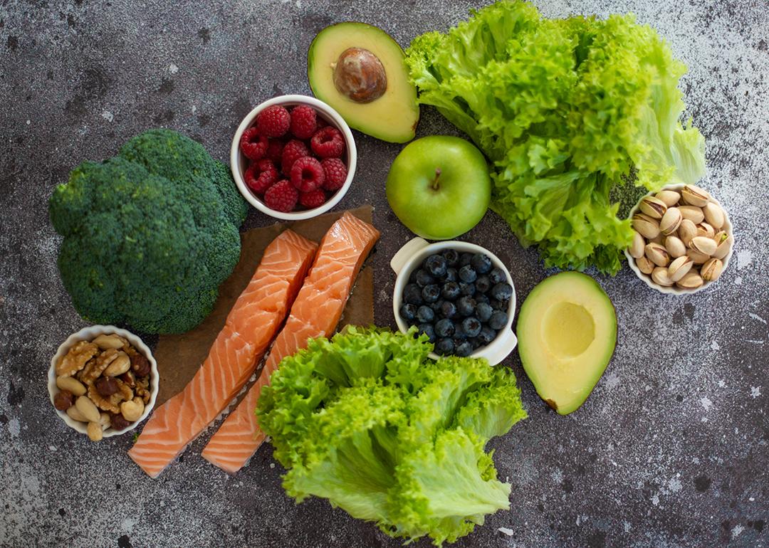A selection of healthy foods such as salmon fish, superfoods, nuts, fruits, berries and leafy vegetables.