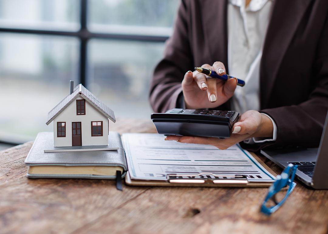 Property agent calculating taxes with a figure of a house and contract on a table.