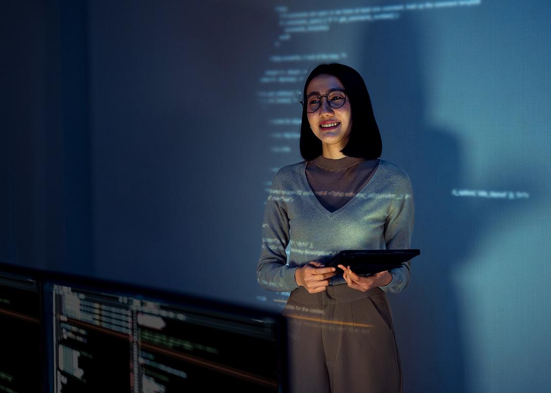 A learning & development employee standing in front of a screen where software lessons are projected.