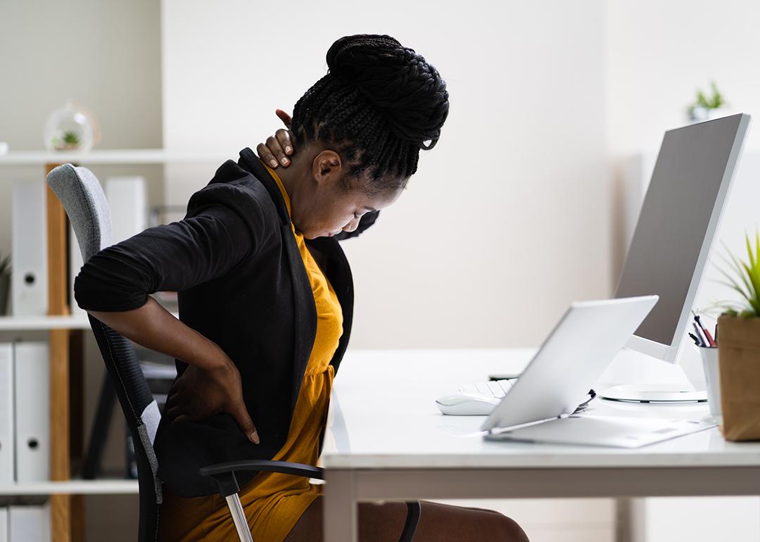 A female employee sitting in her office experiencing back pains.