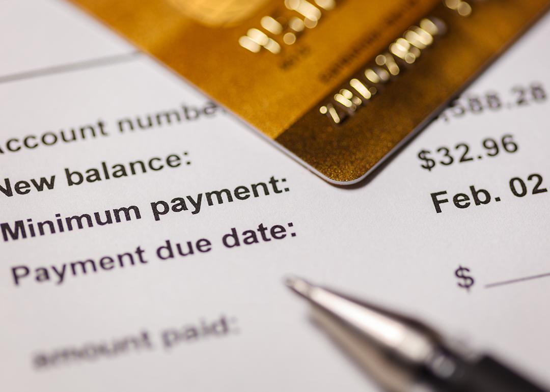 Credit card on top of a bill statement closed up on the minimum amount and due date.