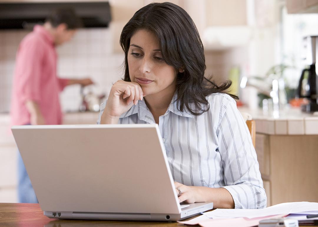 Woman using a laptop at her home's kitchen.
