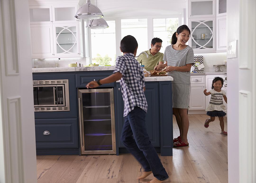 Parents prepare food as their children play around the kitchen.