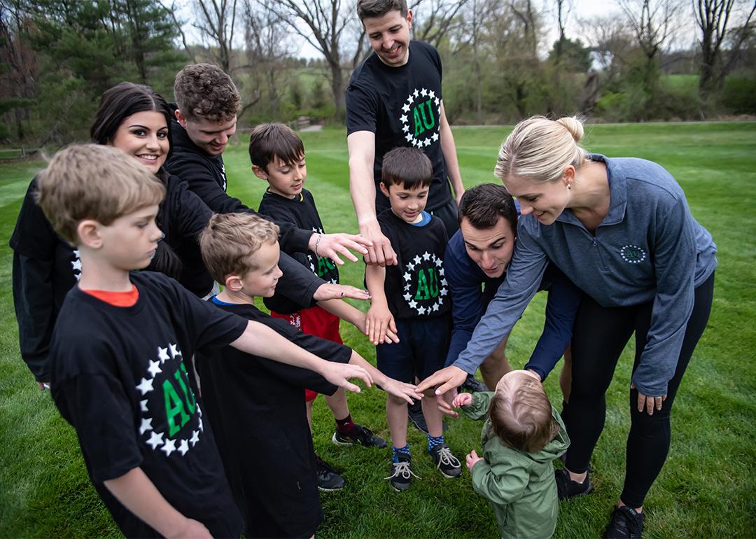 A group of young kinds with their parents form a circle to join hands before a game.