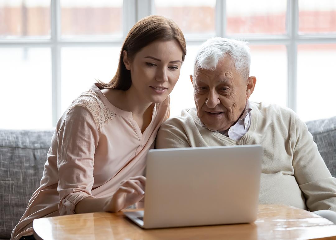 A senior man with his caregiver browsing the internet using a laptop.