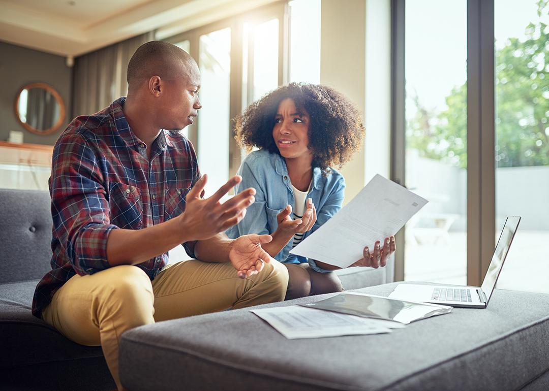 A young couple discussing finances while holding paperwork.