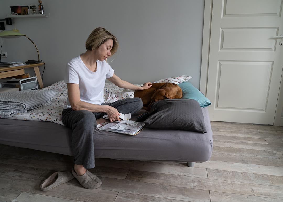 Single middle-aged woman looking at a pile of bills.