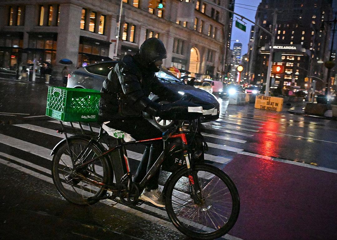 A rider transports a delivery using an e-bike on a street in midtown Manhattan on a rainy night on December 22, 2024 in New York City, USA. 