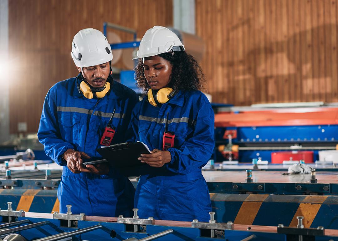 A pair of industrial workers inspect their factory's machines.