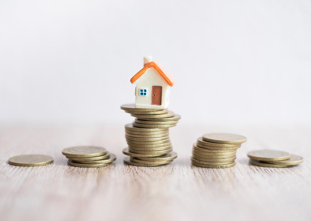A miniature house on top of a stack of coins.