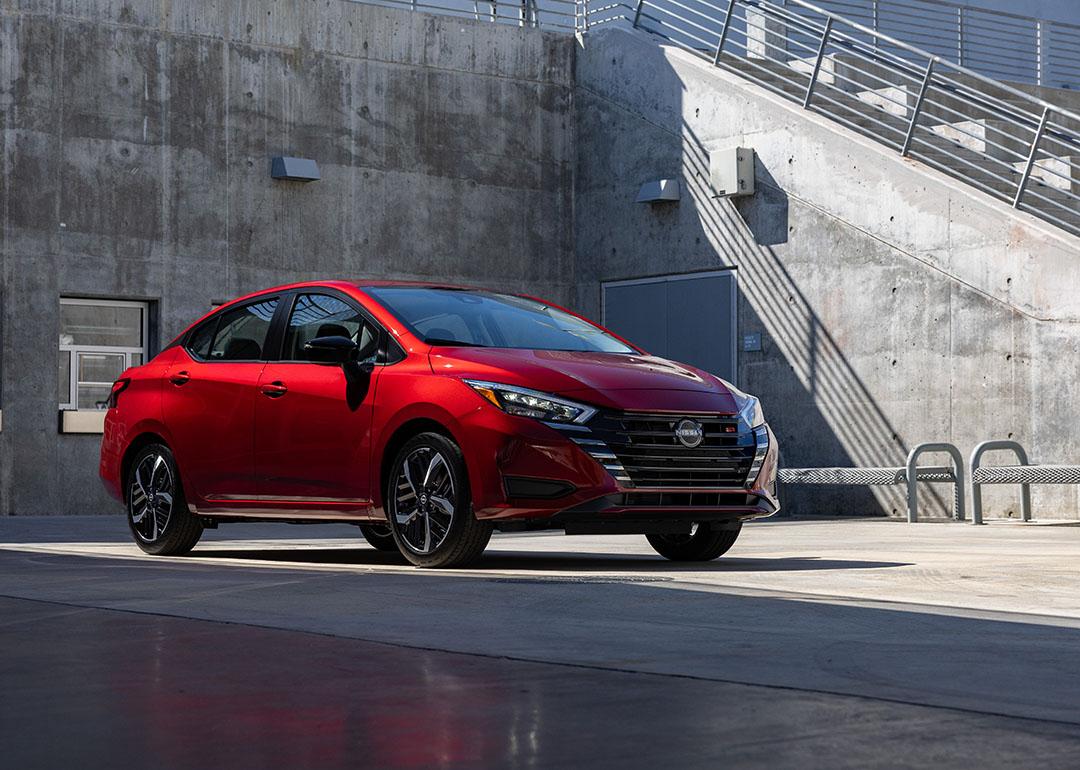 A red 2025 Nissan Versa parked in a concrete lot.