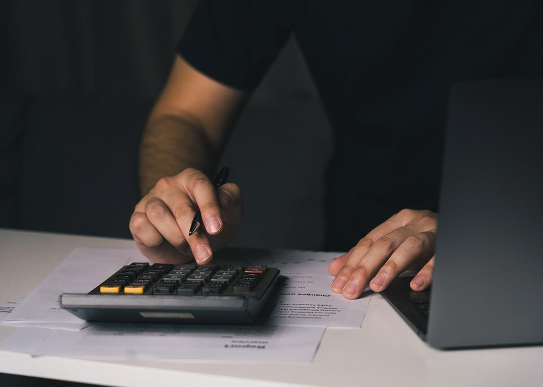 A man uses a calculator to compute monthly expenses.