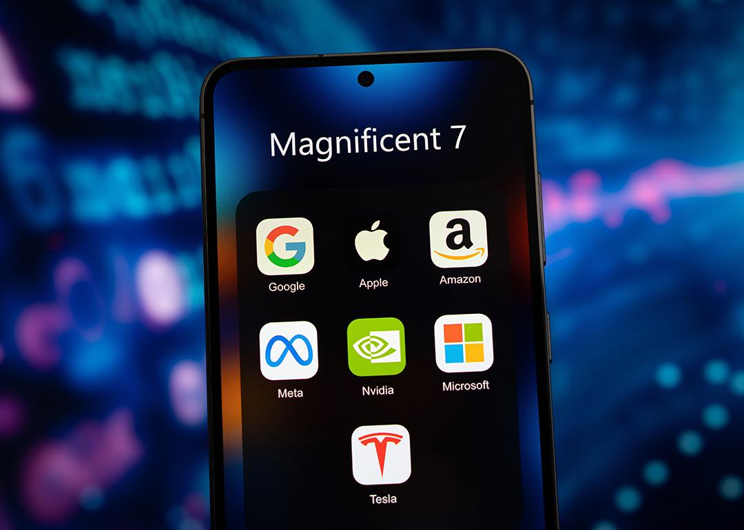 A smartphone's app folder named 'Magnificent 7' and displays app icons of Google, Apple, Amazon, Meta, Nvidia, Microsoft, and Tesla.