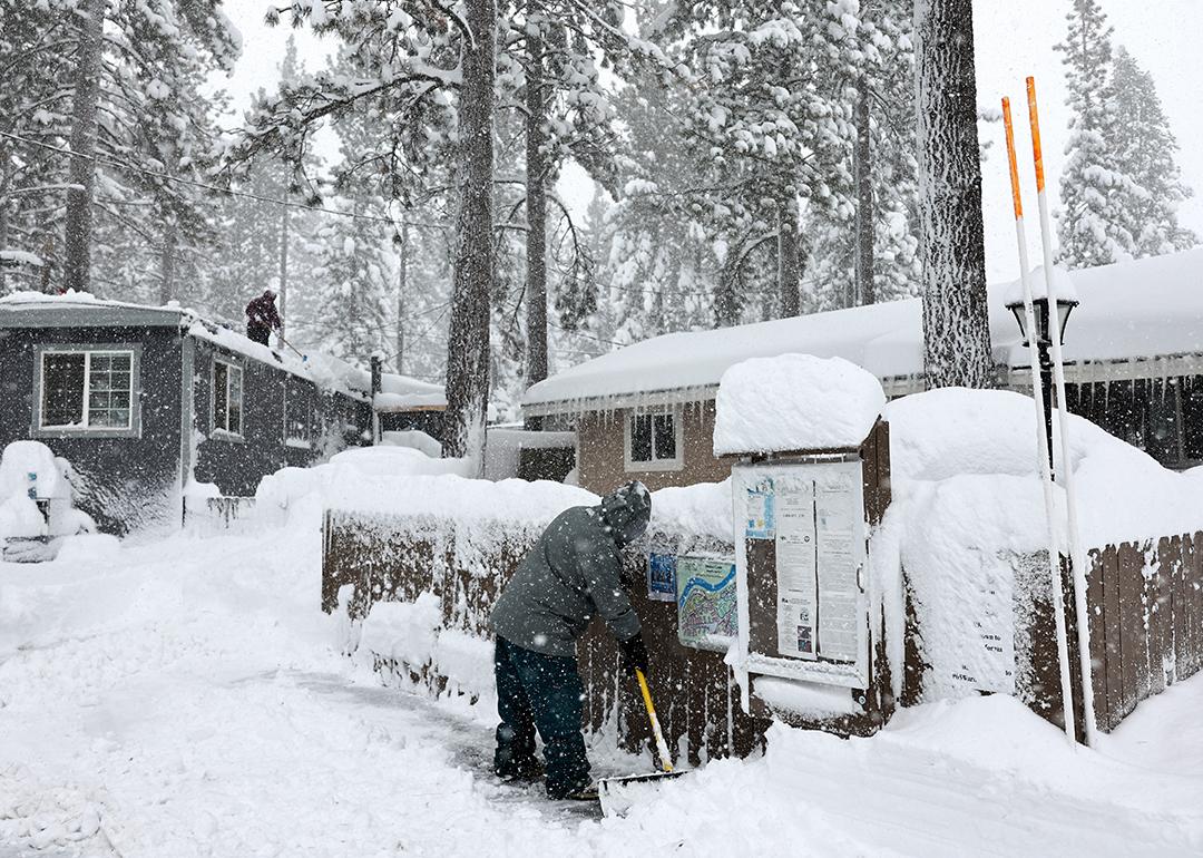 Mobile home owners shovel snow during a winter storm on March 02, 2024 in the Sierra Nevada mountains in Truckee, California.