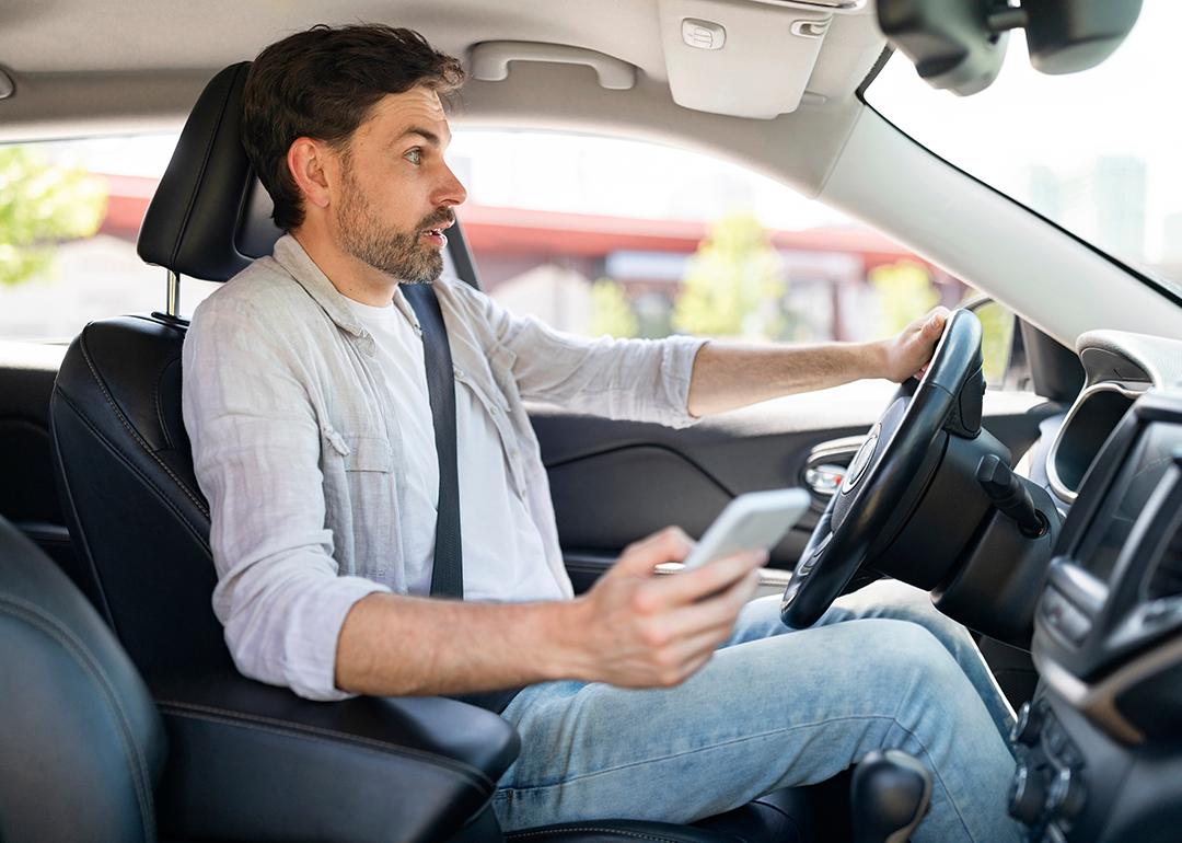 A male driver in shock as he is texting while driving.