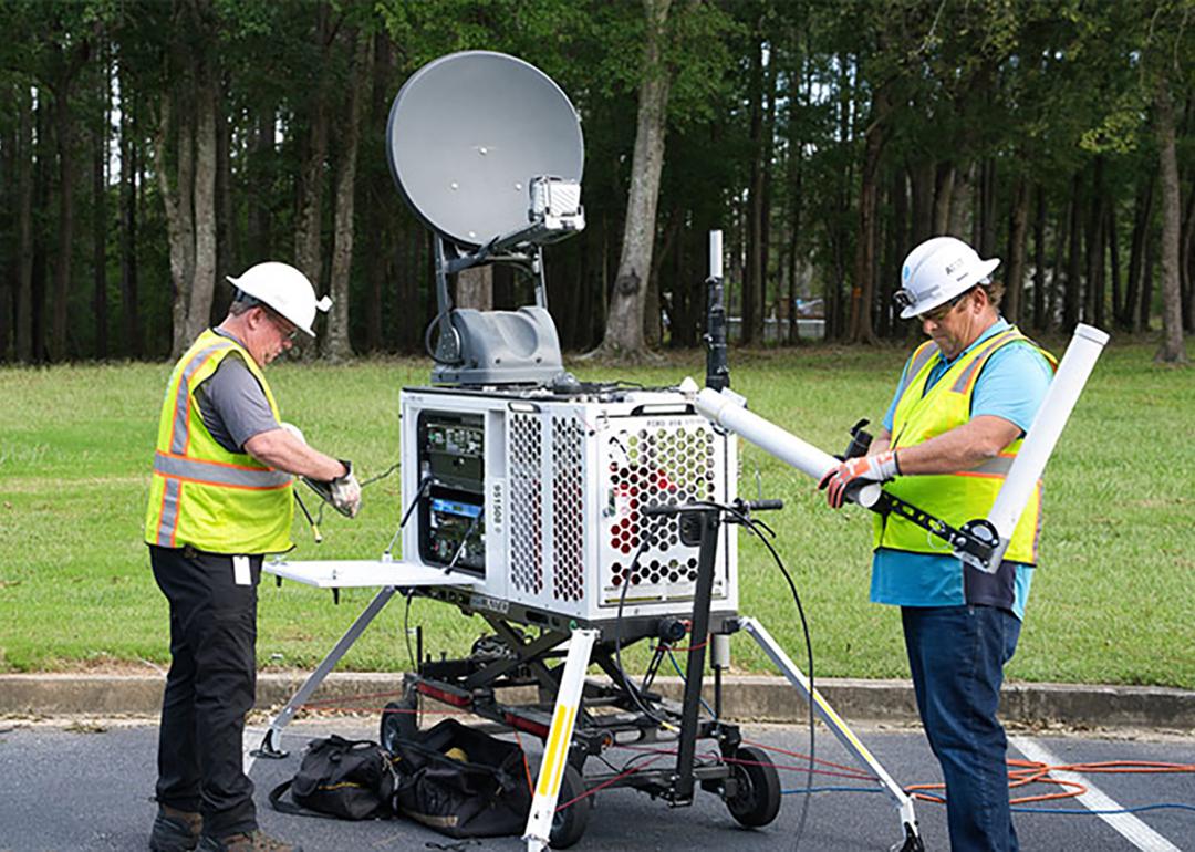 A technical staff setting up a portable satellite asset.