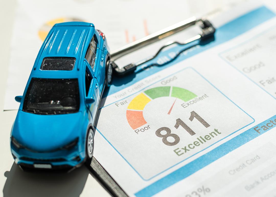 A mini figure of a blue car on top of a credit score report document.
