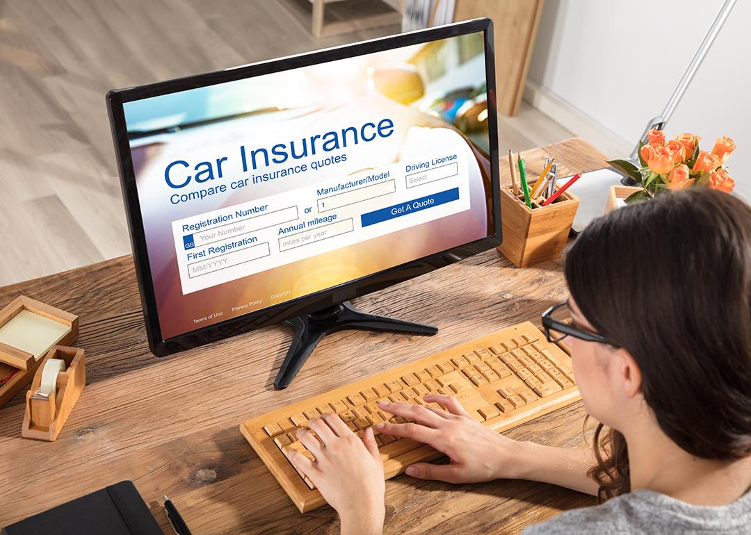 A businesswoman filling out a car insurance form using a desktop.