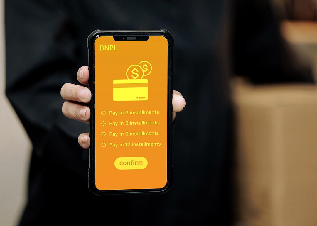 A person holding a smartphone displaying installment options for Buy Now, Pay Later method.