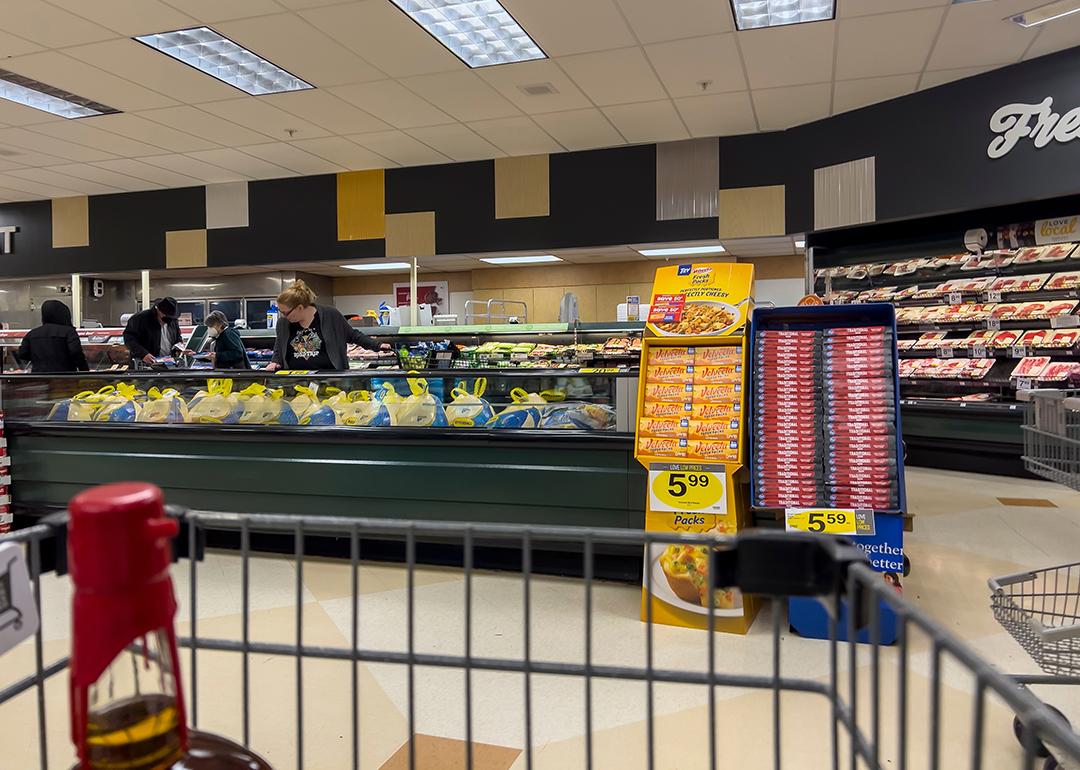 Wide view of people shopping for Butterball Thanksgiving turkeys inside a grocery store.