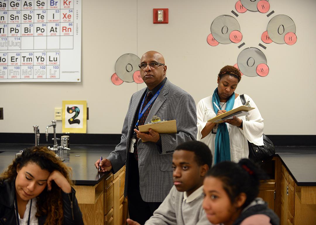 Godfrey Rangasammy, Supervisor of Science, background center, and Tanisha Johnson, a Science Coach, right, background, observe a chemistry class as Literacy coaches at Northwestern High School in Hyattsville, Maryland.