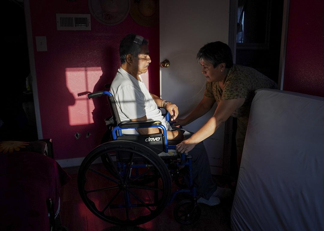 Maria Patricia Alcantara (R), wheels Jose Epifanio Sanchez Trujeque (L) to the bathroom at their home in Lebec, California.
