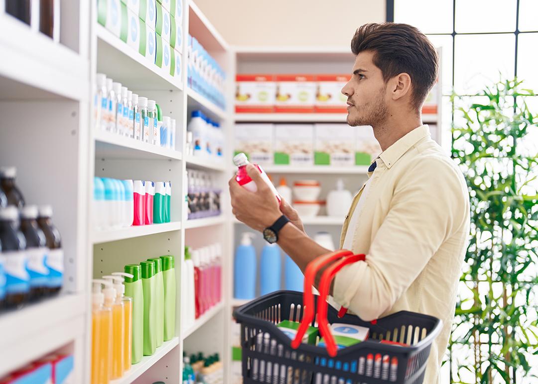 A man holding a basket and shopping at a pharmacy.