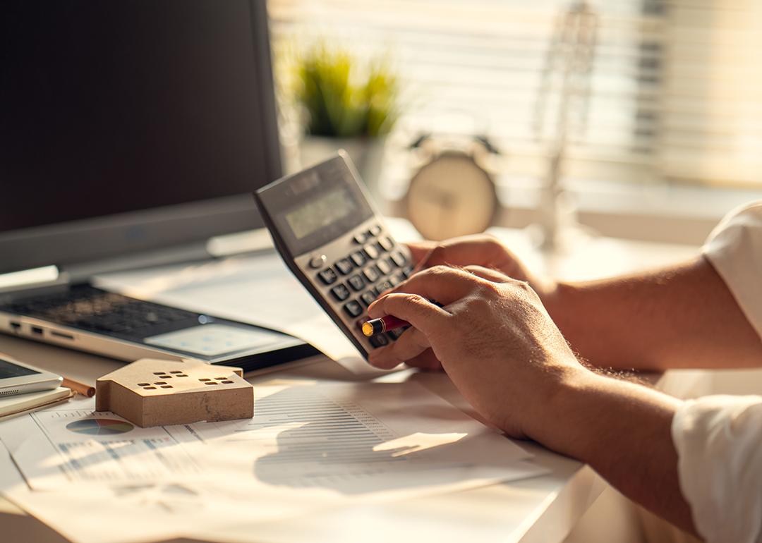 A real estate professional using a calculator over tax documents.