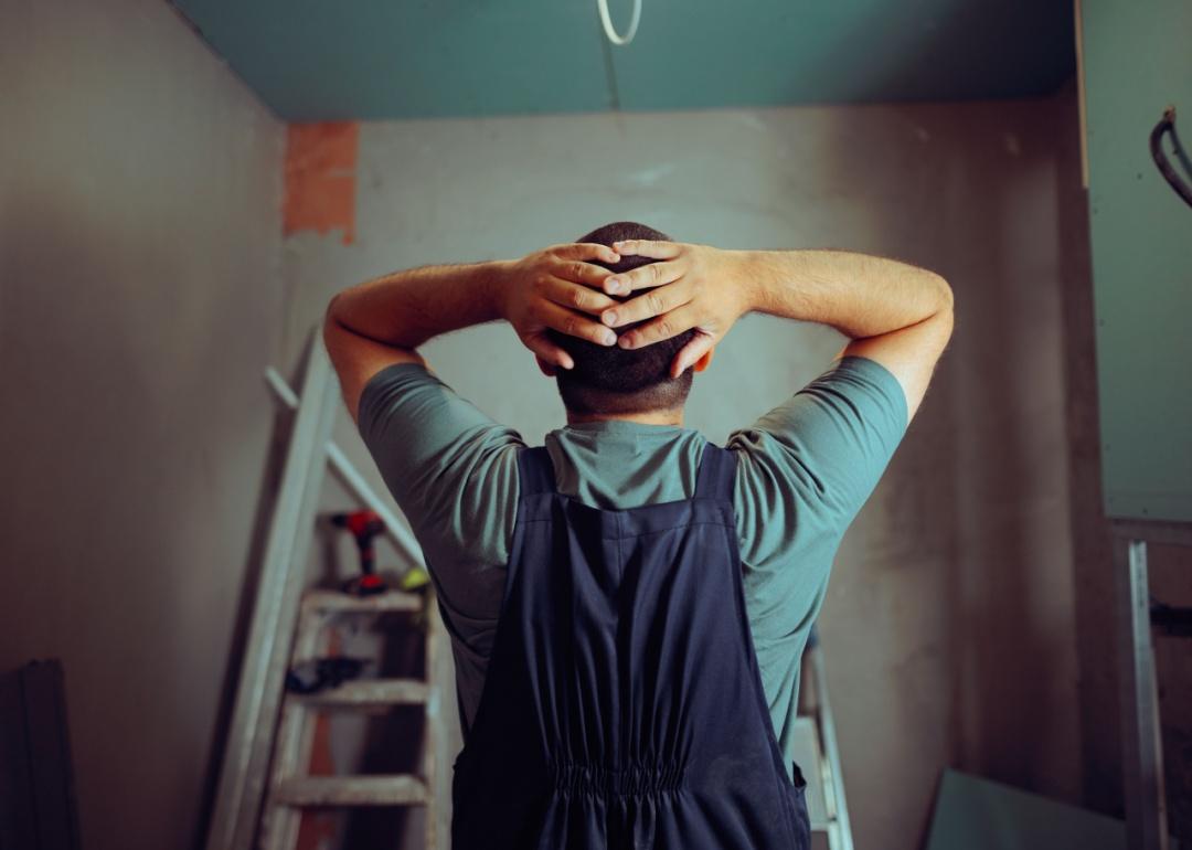Back view of a construction worker with hands on head as he notices mistakes in a project.