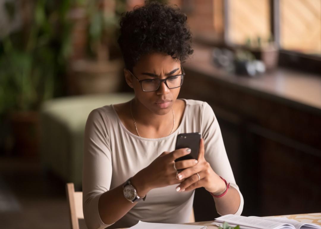 A confused woman looking at her phone.