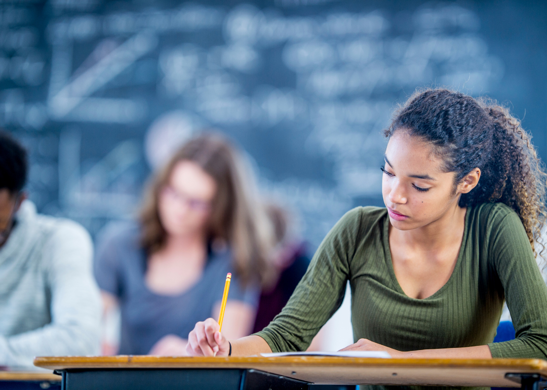 A student writing at a desk.