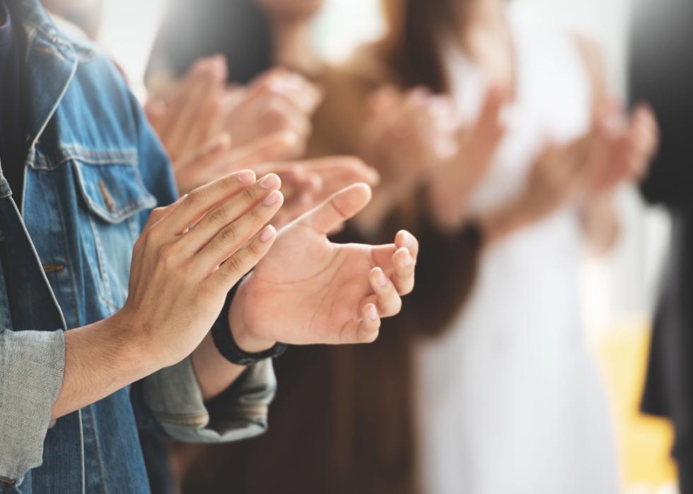 Close-up hands clapping at event.