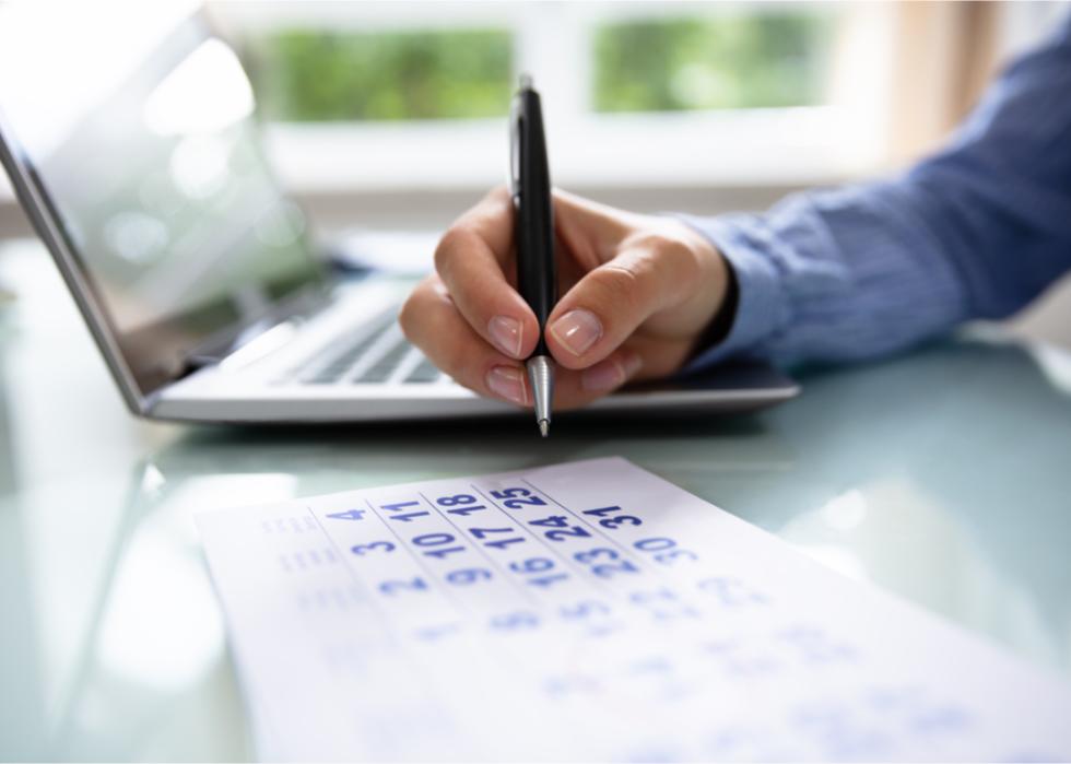 Businessperson hand marks date on a calendar.