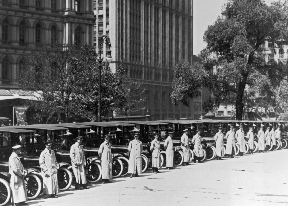 Taxi drivers stand beside new cabs