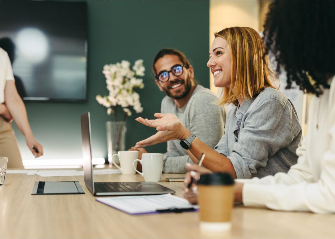 Cheerful businessperson has discussion with colleagues at a conference table.