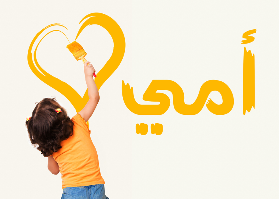 Child painting in Arabic on the wall.