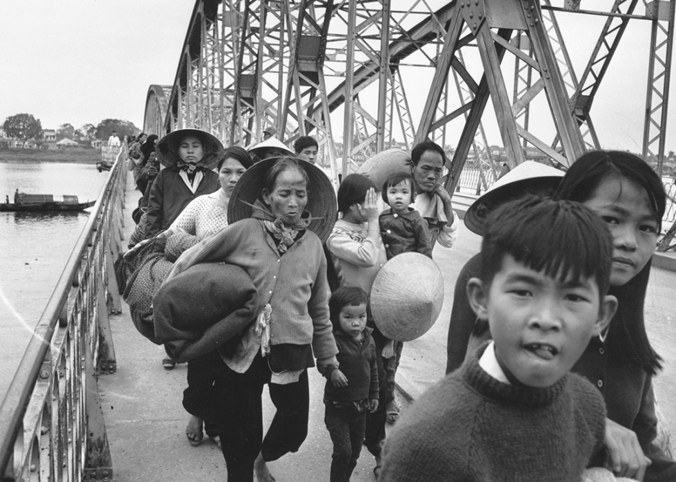 A group of Vietnamese refugees crossing a bridge.