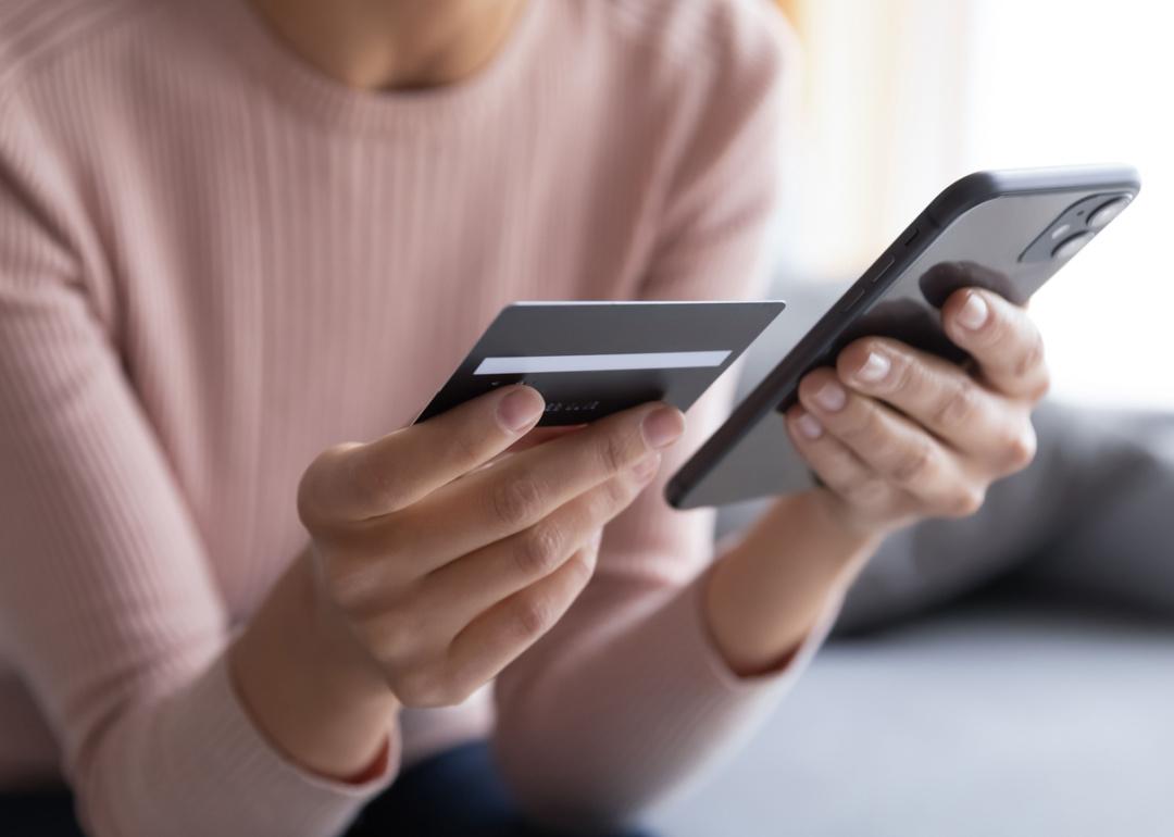 Close up hands holding credit card and phone.